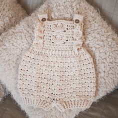 a crocheted baby romper laying on top of a blanket