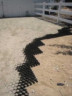 a black pipe laying on the ground next to a white fence