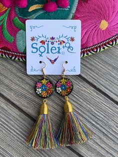 These beautiful earrings are hand painted on wood with silk thread tassels. It is the perfect accessory and pop of color for your outfit! Every piece is completely unique because of the detailed process that goes into creating it. The black lacquer is created by mixing in layers of dirt with a grease from the Cochinilla bug. The flowers are painted on with our finger tips using ground up natural pigments and linseed oil. To finish the process we apply a protective coat to conserve the painting a Multicolor Tassel Earrings For Gifts, Traditional Handmade Multicolor Tassel Earrings, Unique Multicolor Tassel Earrings For Gift, Traditional Multicolor Tassel Earrings With Latkans, Traditional Multicolor Tassel Earrings For Beach, Colorful Tassel Earrings As A Gift, Colorful Tassel Earrings For Gift, Traditional Multicolor Tassel Earrings, Tassel Earrings As A Gift