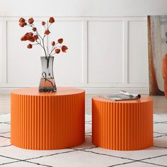 an orange table with two vases and flowers on it in front of a white wall