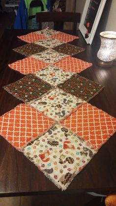 the table runner is made from several different pieces of fabric and has an orange design on it