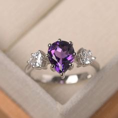 This ring features a 7*9mm pear cut natural amethyst . Customization is available. It is made by hand, and it will take about 7 days to finish the ring after your payment is completed. Main stone: 7*9mm pear cut natural amethyst Main stone weight: 1.79 ct Metal type: 925 silver Accent stone: cz Customization is available, just fee free to contact me, it is free to engrave inside the ring, it is free, you can leave a ntoe with your order, but it will be great no more than 13 letter. Any question, Three Stone Ring, February Birthstone, Cute Rings, Three Stone Rings, Dream Ring, February Birth Stone, Purple Aesthetic, Silver Accents, Pear Cut