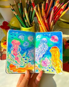 an open notebook with colored pencils in it and jellyfish drawings on the pages