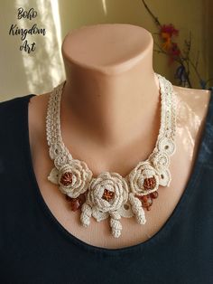 a crocheted necklace is displayed on a mannequin neckline with flowers