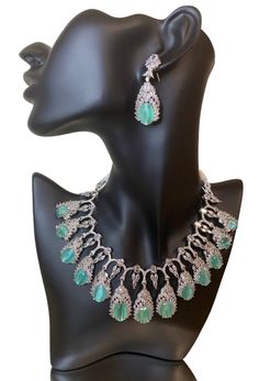 This CZ American Diamond Necklace is the perfect accessory for any outfit and any occasion. Its high-quality CZ American Diamond stones add a touch of elegance to any look, whether it's a silk saree, gown, lehanga, or more. The mint colorstone also adds a pop of color to your ensemble. Upgrade your jewelry collection with this versatile and beautiful necklace. This jewellery set includes a necklace and matching earrings. Jewellery Care- Keep the jewellery dry, avoid contact with perfumes and water. Elegant Kundan Necklace With American Diamond For Formal Occasions, Elegant Jewelry With Stone Setting In American Diamond, Elegant Kundan Jewelry Sets With Stone Setting, Elegant Jewelry With Stone Setting In Faux Diamond, Elegant American Diamond Jewelry With Stone Setting, Elegant American Diamond Jewelry Sets For Festive Occasions, Elegant Party Jewelry Sets With Stone Setting, Luxury American Diamond Jewelry Sets For Party, Elegant Crystal Necklaces For Reception