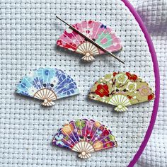 three colorful fan shaped pins sitting on top of a table