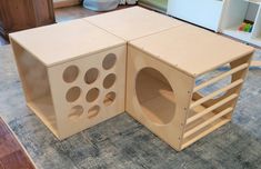 two wooden boxes with holes cut into them on the floor in front of a bookcase