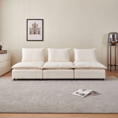 a living room filled with furniture and a white rug on top of a hard wood floor