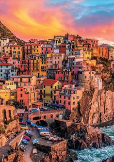 the colorful buildings are on top of the cliff by the ocean at sunset or sunrise