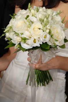 a bride holding a bouquet of white flowers