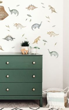 a green dresser sitting in front of a wall with dinosaur decals on it's walls