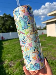 someone holding up a cup with an animal pattern on it in front of a house