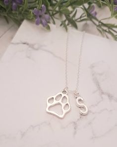 "This Paw Charm Necklace is the perfect gift for someone special!  The necklace is sterling silver 925. This makes an excellent gift for yourself or your friends and family members who loves pets! Product Details: Material: Sterling silver necklace Chain Length: 18 Inches (Can be made in different lengths) Charms: Paw Charm and Initial Charm (Initial Charm can be personalized) This Initial charm necklace can be personalized according to your choice. Please reach out to me for customizations.  You can get these personalized necklaces in any length, so please contact me via Etsy Conversations if you need any size. This exquisite 18\" snake chain necklace comes with a paw charm and a silver letter initial charm that can be customized according to your choice. This minimalist and dainty neckla Hypoallergenic Sterling Silver Dog Tag Jewelry, Sterling Silver Dog Tag Jewelry For Gift, Sterling Silver Dog Tag Jewelry Gift, Silver Paw Print Jewelry As Gift, Sterling Silver Paw Print Jewelry For Gifts, Sterling Silver Paw Print Necklace For Gift, Sterling Silver Paw Print Jewelry Gift, Sterling Silver Paw Print Necklace As Gift, Silver Hand Stamped Necklace For Best Friend