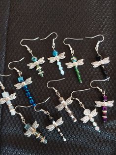 six pairs of dragonfly earrings on a black cloth with white beads and crystal stones