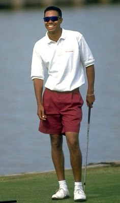 a man in red shorts and white shirt holding a golf club