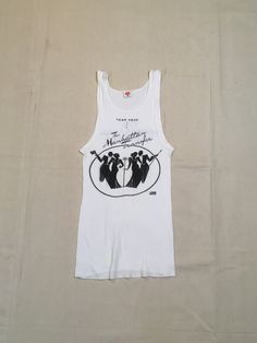 "1970s band tanktop shirt Hanes, cotton, white ribbed The Manhattan Transfer black print Atlantic Records symbol at lower right of image front/back image good vintage condition, light wear light stains, light cracking label size M, see below measures, lying flat, chest-12\" unstretched to 19\" stretched length-26\"" Fitted Sleeveless Cotton T-shirt, Vintage Tank T-shirt For Summer, Retro White Tank Top For Streetwear, Fitted 90s Crew Neck Tank Top, Vintage Cotton Muscle Tee With Crew Neck, Vintage Cotton Crew Neck Muscle Tee, Retro Stretch Tank Top With Graphic Print, 90s Style Stretch Cotton Tank Top, Retro Racerback Top