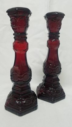 two red glass candlesticks sitting next to each other on a white tablecloth