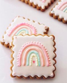 cookies decorated with rainbows and hearts on a white tableclothed surface, ready to be eaten