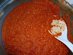 a large pot filled with red sauce and a white spoon