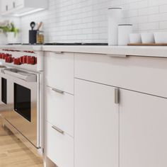 a kitchen with white cabinets and stainless steel appliances, along with red cups on the counter