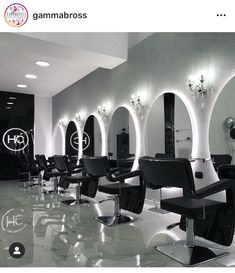 the interior of a hair salon with black chairs and mirrors on the wall above them