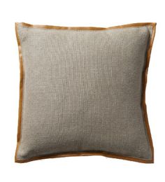 a beige and brown pillow with contrasting piping on the front, sitting against a white background