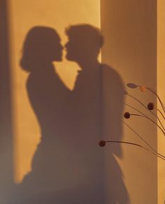 the shadow of two people kissing in front of a wall