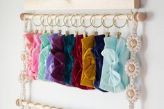 there are many different colors of fabric hanging on the wall with clothes pins attached to it