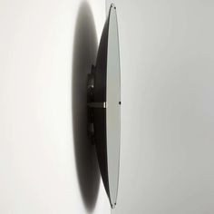 a circular mirror mounted to the side of a white wall next to a black clock