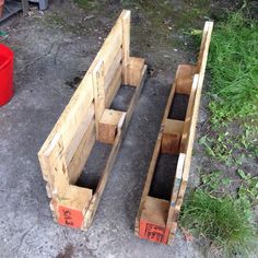 two wooden boxes sitting on the ground next to some grass and red buckets with dirt in them