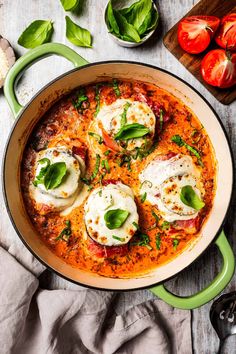 a pan filled with ravioli and cheese on top of a wooden table next to tomatoes