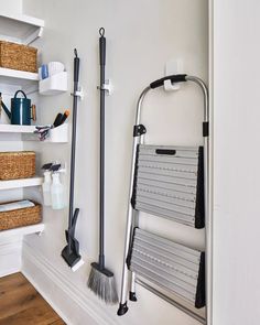 two brooms are hanging on the wall next to a rack with cleaning supplies in it