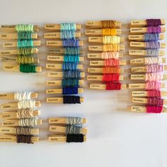 several spools of thread are arranged in rows on a white surface with wooden skewers