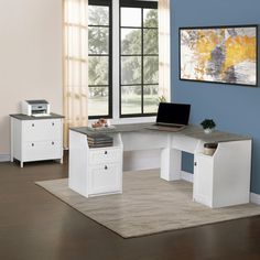 a computer desk with two drawers and a laptop on it in front of a window