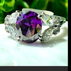 a ring with an amethorate surrounded by white and purple stones on it