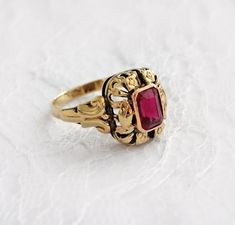 Vintage 14K gold ring dating from at least as far back as the 1970s - may be older - with a synthetic ruby faceted rectangle gemstone. Gorgeous open floral detail. The ring is not hallmarked, but it looks like there were once markings that faded with wear.On my screen, the color is more true in the photos than on the video. Different screens may vary in how they show colors.SIZE:US 7WEIGHT:2.7 gramsMETAL:14K Gold (Tested, unmarked)GEMSTONE:Synthetic rubySTONE SHAPE:OctagonSTONE SIZE:7.5x5mmCONDI Ruby Statement Ring, Vintage Ruby Gold Rings, Victorian 14k Gold Ruby Ring With Intricate Design, Ornate Yellow Gold Ruby Ring Gift, Ornate Gold Ruby Ring, Vintage Gold Ruby Ring With Filigree, Ornate 14k Gold Ruby Ring For Anniversary, Antique 14k Gold Ruby Ring With Intricate Design, Vintage Yellow Gold Ruby Ring