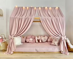 a pink canopy bed with pillows and lights