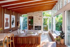 a living room filled with furniture next to a fire place under a wooden ceiling covered in windows