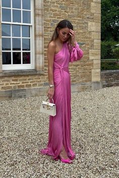 a woman in a pink dress is standing outside