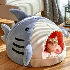 a cat in a shark shaped bed on the floor