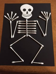 a skeleton made out of sticks on top of a black board with white stickers