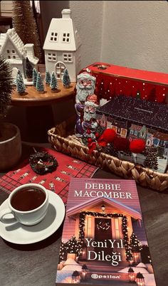 a cup of coffee sitting on top of a table next to a book and christmas decorations