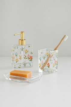 a soap dispenser, toothbrush holder and soap bar on a white surface