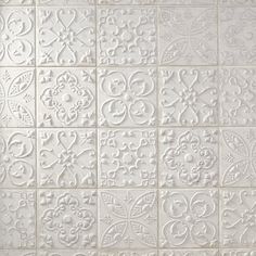 a white tile wall with many different designs on it