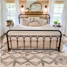 a bedroom with a metal bed frame and pillows on top of it, along with two windows