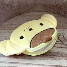 a stuffed animal in a yellow pouch sitting on a table next to a key chain