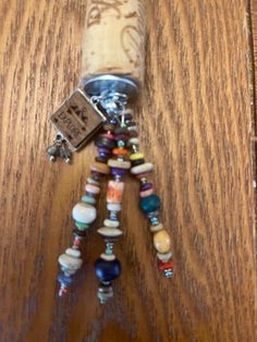 a bottle with some beads on it sitting on top of a wooden table next to a keychain