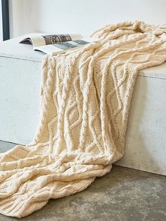 a white blanket sitting on top of a cement floor next to a window sill