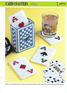 four playing cards and a glass on a yellow surface with a candle holder in the middle