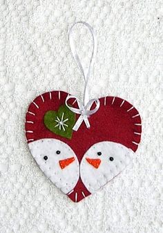 a heart shaped ornament with two snowmen on it